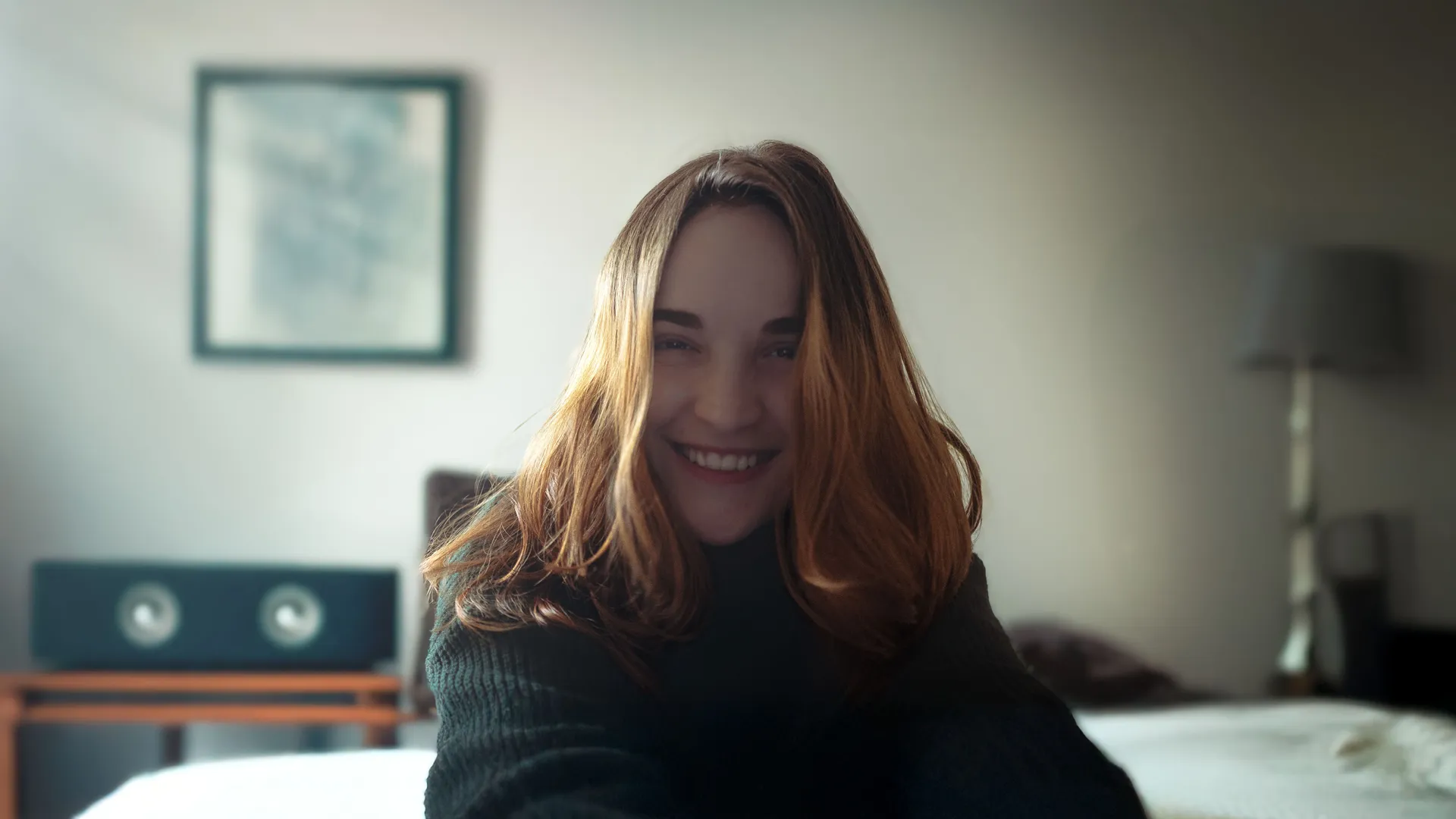 Maria smiling at home, sitting on her bed in soft morning light